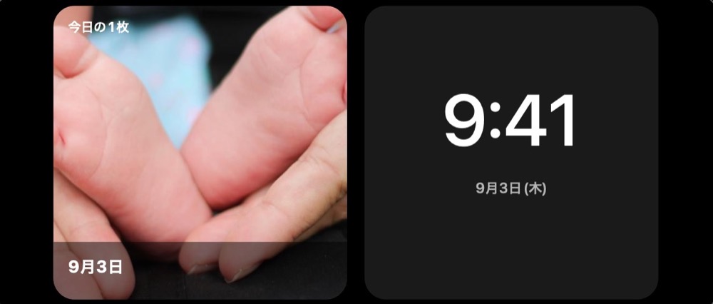 充電台に横向きに置いた iPhone のスタンバイ画面に、時計と今日の1枚が並んでいる