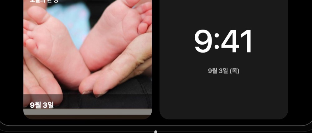 충전대에 가로로 놓인 iPhone의 스탠바이 화면에 시계와 오늘의 사진이 나란히 표시되어 있다
