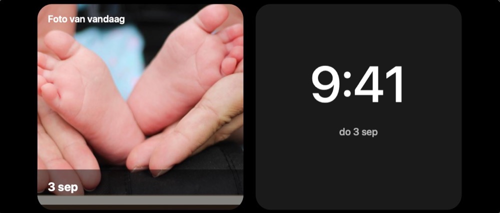 Een iPhone staat dwars op een oplader en toont in Stand-by de klok naast de foto van vandaag.